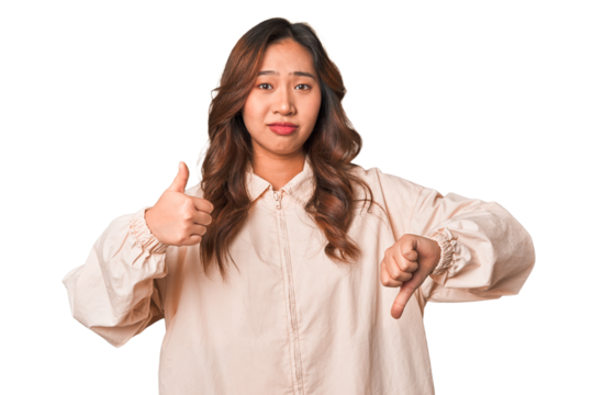 A young chinese woman showing thumbs up and thumbs down, difficult choose concept