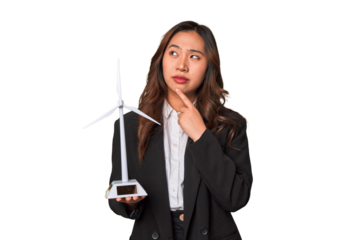 A young Chinese businesswoman proudly holds a windmill, symbolizing her commitment to renewable energy and sustainable development.