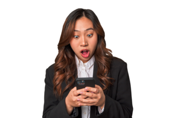 A young Chinese businesswoman looks surprised while glancing at her phone, perhaps receiving unexpected news or a message that has left her amazed.