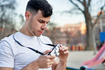 Young caucasian man capturing memories with his vintage camera in the park.