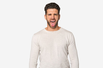 Young handsome man isolated funny and friendly sticking out tongue.