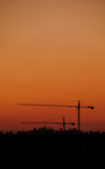 Orange sunset with construction cranes