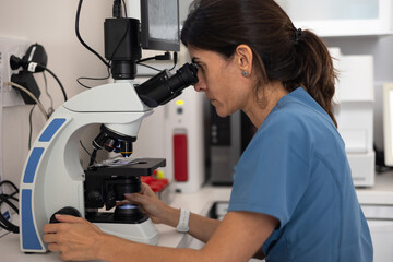 side view of female veterinarian looking through the microscope of the microscope.