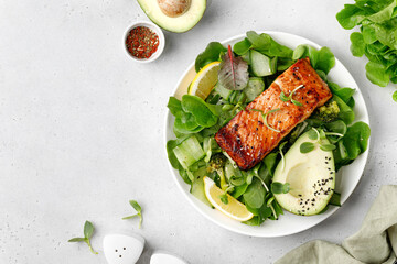 Baked roasted salmon steak with green healthy salad with avocado. Fresh diet dinner meal. Vitamin food concept on the plate and grey background.