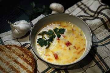 creamy vegetable soup on dark background, rustic village style, rosted bread, garlic, textile napkin