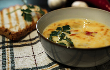 creamy vegetable soup on dark background, rustic village style, rosted bread, garlic, textile napkin