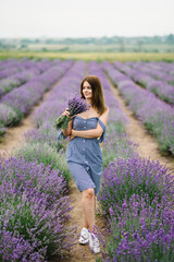 Beautiful girl hold bouquet purple lavender flowers in field. Female collect lavender. Woman in the lavender field. Enjoy the floral glade, summer. Down view. Close up