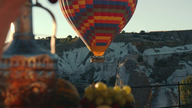 Close-Up of hot air baloon on sunrise in Cappadocia. Forefront young woman picking berries.