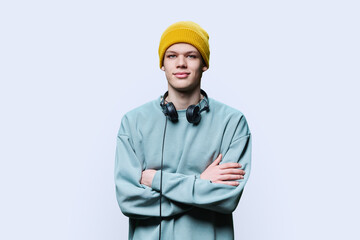 Young male in yellow cap sweatshirt with headphones on white background