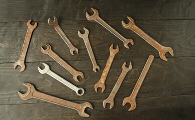On a wooden background there are many different wrenches, of different sizes.  Conceptual construction and hand tools.  Flat lay, top view.