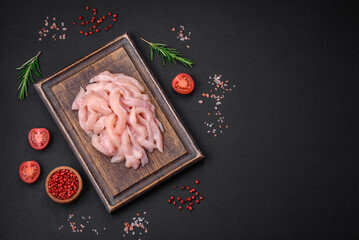 Raw chicken fillet cut into strips with spices and herbs