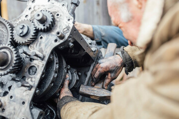 tractor car engine repair at home, old man repairs the engine.