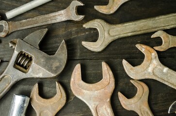 On a wooden background are wrenches and adjustable wrenches of different sizes and numbers.  Flat lay top view.  Close-up, background image.