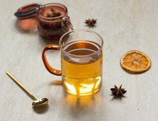 Tea in glass cup on table with dried orange, anise and spoon, tea time concept