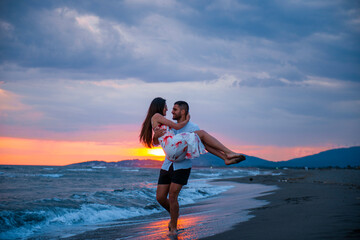 Sunset Romance: Man Carrying Woman on Beach