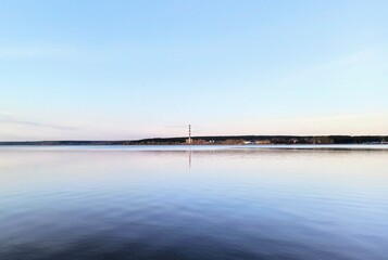 in the distance there is an industrial pipe against the backdrop of calm water