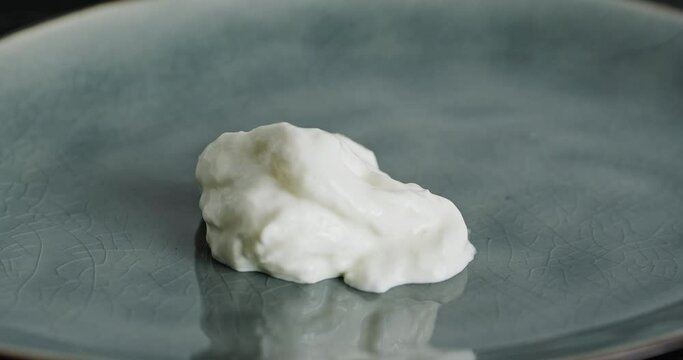 Putting stracciatella cheese on plate with fork. Italian mozzarella, stretched curd cheese shreds, Stracciatella di bufala, close up video clip, high quality 4k footage