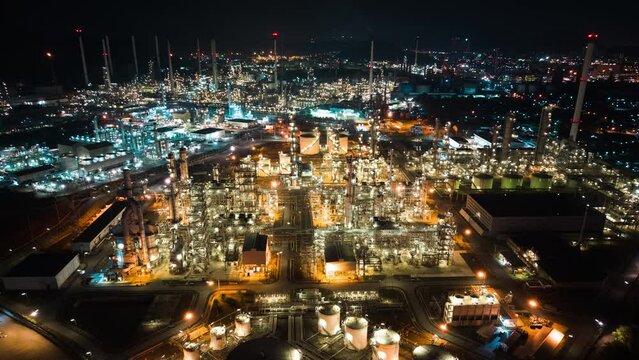 Hyperlapse time lapse of petroleum oil refinery in industrial estate at night, drone aerial view. Fuel and power generation, petrochemical factory industry, or environmental air pollution concept