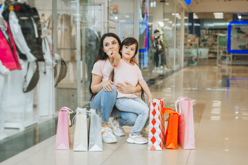 young mother and daughter holding shopping bags, shopping in the mall. Family shopping.