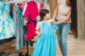 Fototapeta na wymiar mother and daughter buy clothes. mother and little girl trying on clothes in the shop