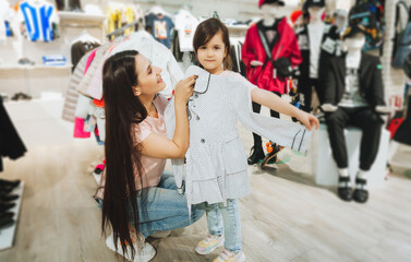 mother and daughter buy clothes. mother and little girl trying on clothes in the shop