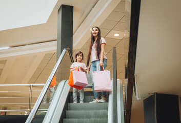 mother and little girl on the escalator in the mall.Mother and daughter in the mall. A young mother...