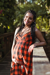 Beautiful Hispanic woman with braids full of joy enjoys her pregnancy. Healthy pregnancy concept