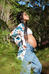 young pregnant woman breathing with eyes closed and smiling, pregnant in nature, happy mother, healthy pregnancy