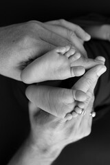 Black and white shade beautiful shape hands of mother, hold tiny newborn baby feet on black background with love, care, family safety and protection, child with premature birth concept or NICU care