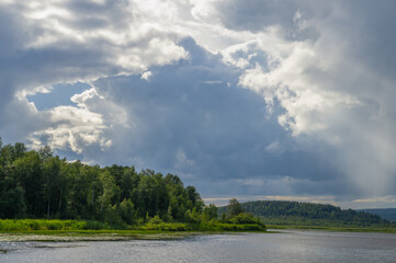 Beautiful thundercloud with sunbeams, summer day on the lake.