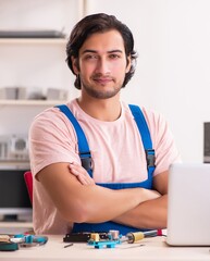 Young male contractor repairing computer