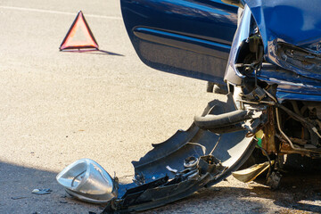 Car accident. A broken-down passenger car is on the road after an accident. Road sign of an...