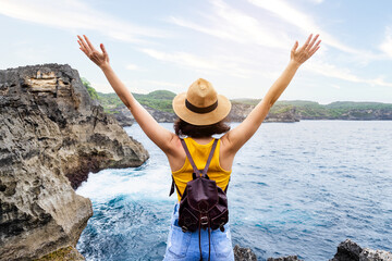 Back view of happy woman with arms up enjoying vacation on Nusa Penida, Bali. Female enjoying freedom in nature. © Daniel