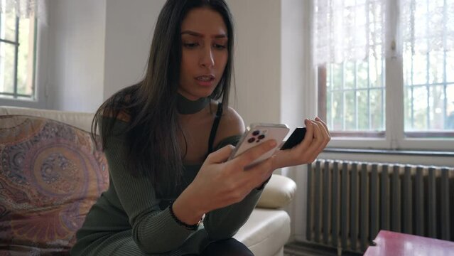 One young brunette woman doing online payment with cellphone device at home. Adult girl putting credit card information