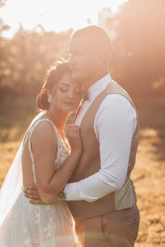 Wedding photo. The bride and groom are standing in a beautiful forest and beautiful light, hugging. Couple in love. Stylish groom. Portrait