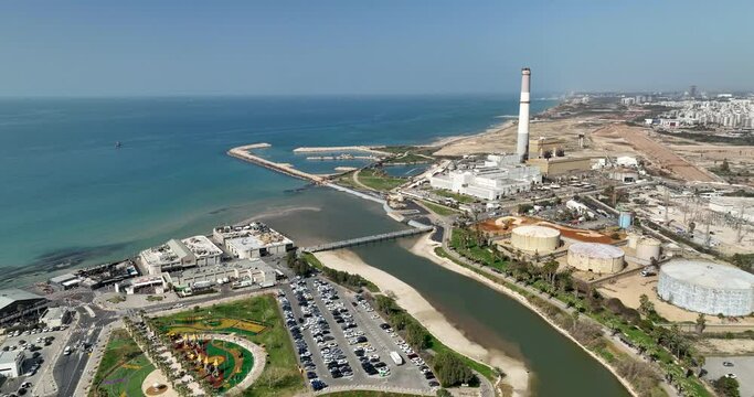 Aerial footage of the Yarkon River with the power plant in the background on the shore of the Mediterranean Sea. Filmed in C4K Apple ProRes 422 HQ