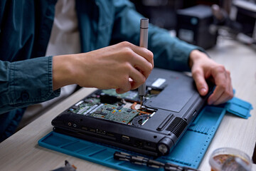 Closeup of unrecognizable engineer technician hands repairing faulty on laptop computer in electric device technology service, male using special tools. Maintenance notebook support service engineer