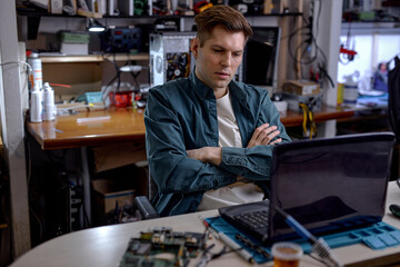 caucasian professional technician sit thinking how to repair fault laptop, sit behind table at...