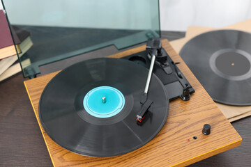 Retro turntable with vinyl record on wooden table