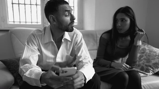 Boyfriend addicted to technology while ignoring girlfriend sitting on couch at home. People obsessed to social media. Loneliness addiction concept