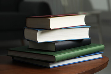 Stack of hardcover books on wooden coffee table indoors, closeup