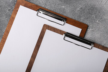 New wooden clipboards with sheets of blank paper on grey textured table, flat lay
