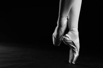 Ballerina in pointe shoes dancing, closeup with space for text. Black and white effect
