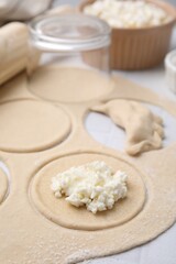 Fototapeta na wymiar Process of making dumplings (varenyky) with cottage cheese. Raw dough and ingredients on white table, closeup