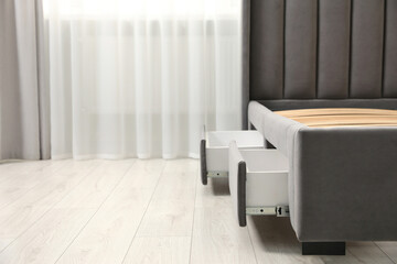 Fototapeta premium Storage drawers for bedding under modern bed in room. Space for text