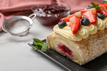 Tasty meringue roll with jam, cream, strawberry, blueberry and mint on white table, closeup. Space for text