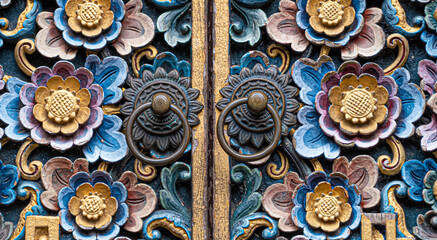 Colorful carved wood doors with brass door knob rings