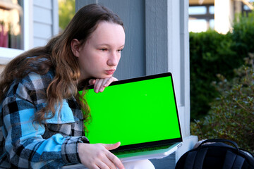 young pretty student woman bored tired over worked on her laptop wearing a black shirt isolated on green screen cromakey - chormakey or chroma croma key for composite. High quality photo