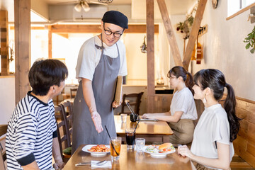 客に料理の説明をするカフェ・飲食店のホールスタッフ・従業員の男性
