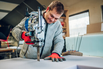 A satisfied artisan is using foam cutter at his workshop.